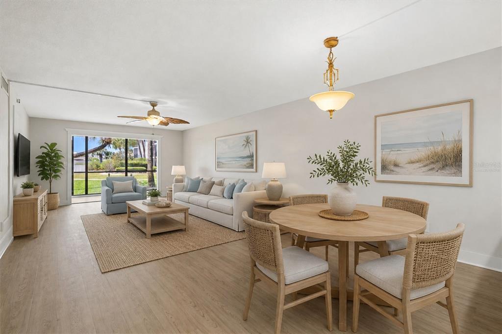 A bright living and dining area with light wood floors, neutral furniture, and coastal decor — 5600 BEACH WAY DRIVE UNIT 109, SARASOTA, FL