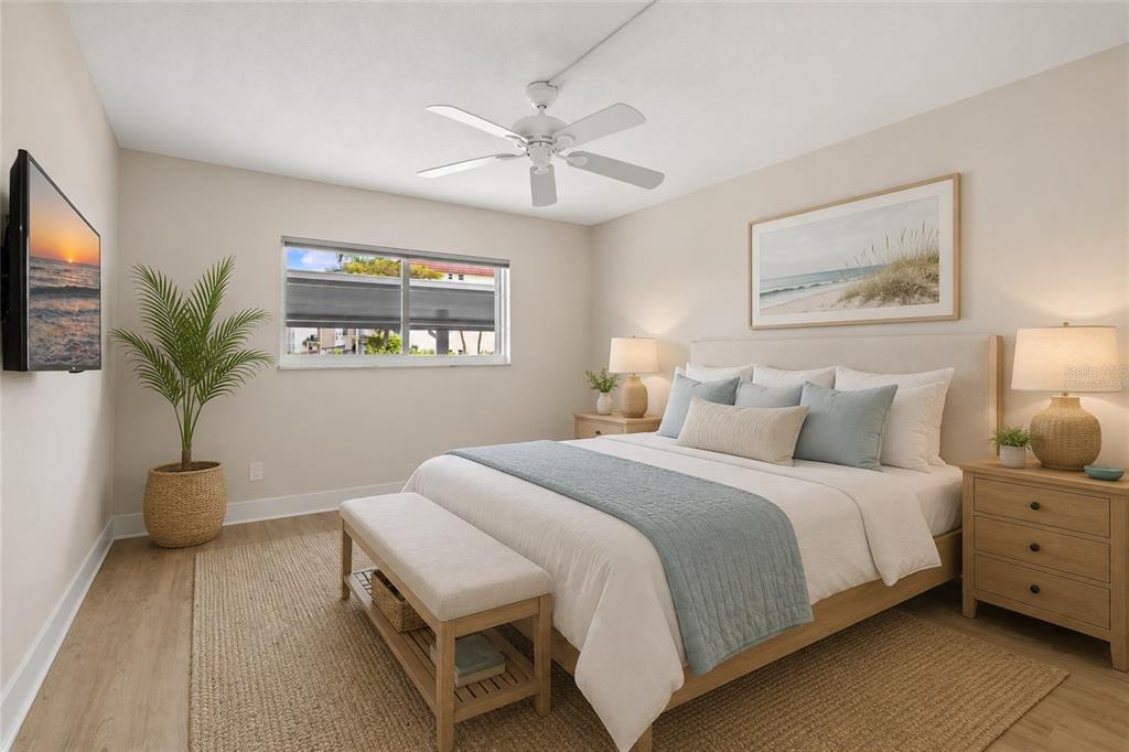 A bedroom features a queen bed, light wood flooring, a ceiling fan, and a wall-mounted television — 5600 BEACH WAY DRIVE UNIT 109, SARASOTA, FL