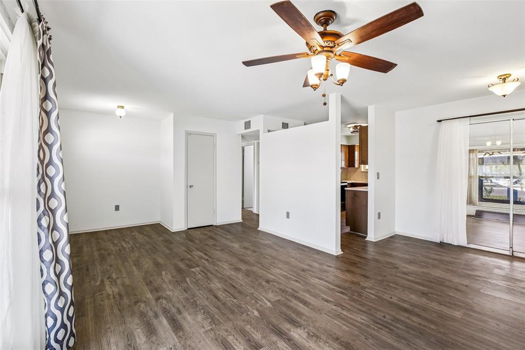 An open-concept living room features wood-look flooring, a ceiling fan, and a partial wall — 704 OJAI AVENUE, SUN CITY CENTER, FL