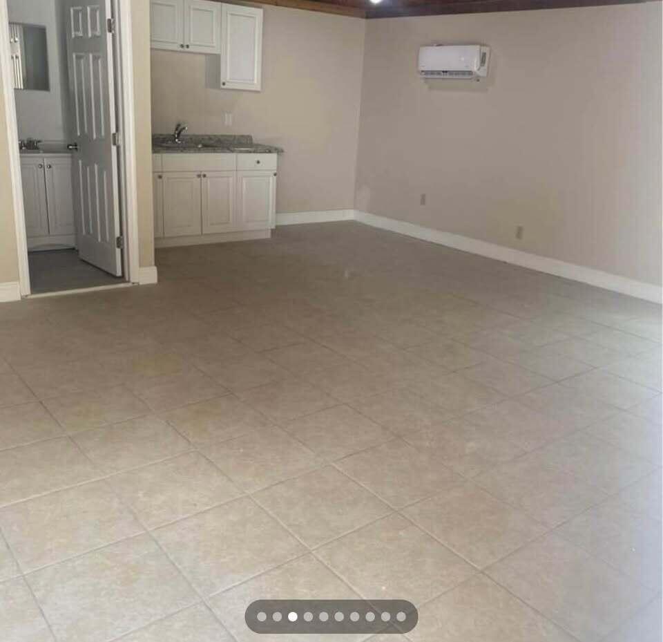 An interior view of a room with light-colored tile flooring, a kitchenette, and wall-mounted AC — 952 30th Street, West Palm Beach FL 33407, WEST PALM BEACH, FL