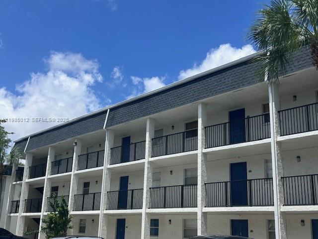A three-story apartment building features white exterior walls, dark railings, and a dark shingled roof — 5100 SW 64th Ave # 202, Davie FL 33314, DAVIE, FL