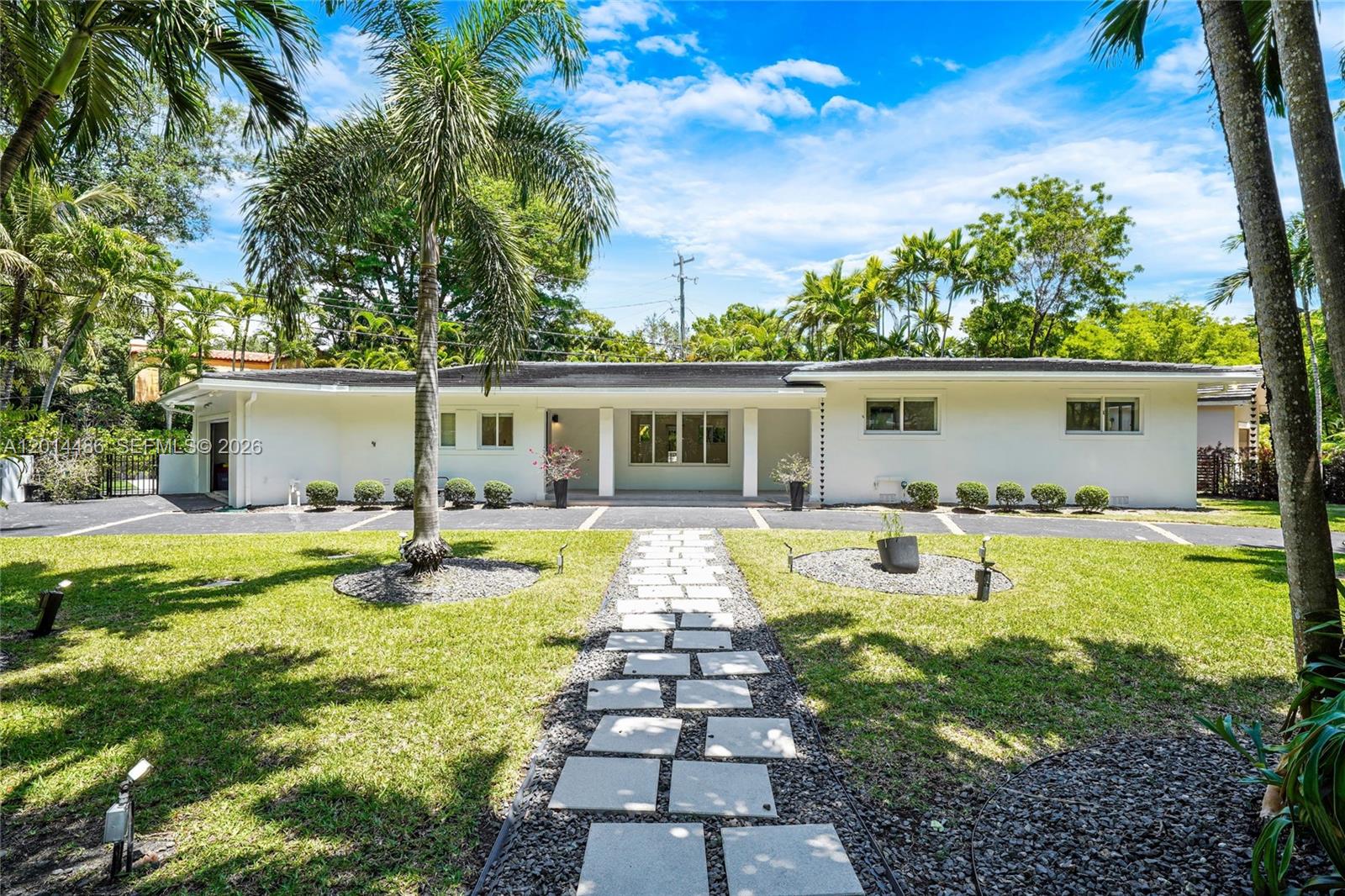 A single-story white house with a flat roof features a stone walkway and palm trees — 711 Sunset Dr, Coral Gables FL 33143, CORAL GABLES, FL