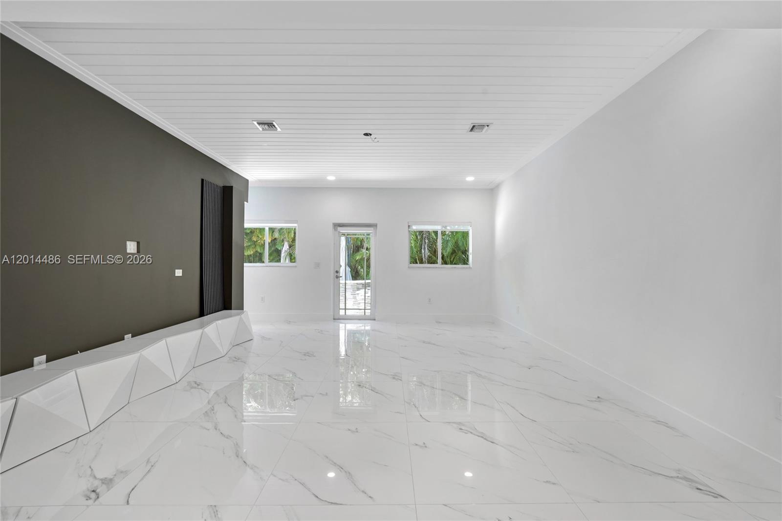 A bright living room features white marble floors, a dark accent wall, and a slatted ceiling — 711 Sunset Dr, Coral Gables FL 33143, CORAL GABLES, FL