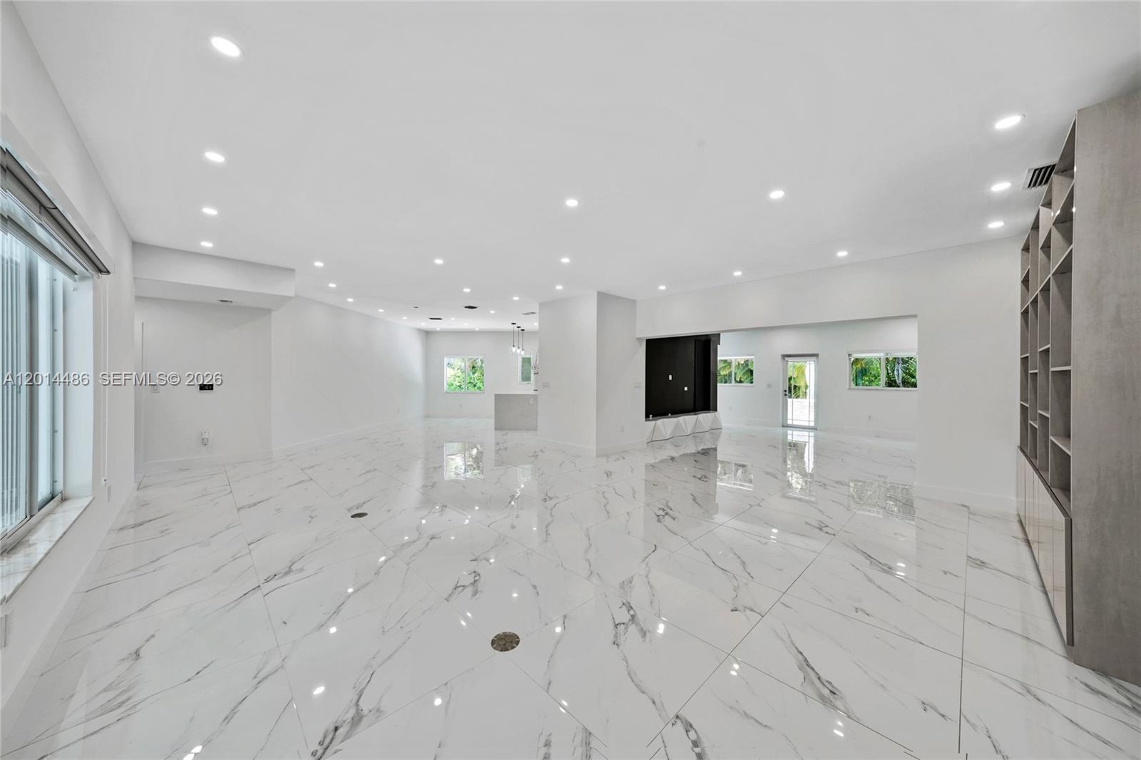 A spacious, open-concept living area features white marble-look tile flooring and built-in shelving — 711 Sunset Dr, Coral Gables FL 33143, CORAL GABLES, FL