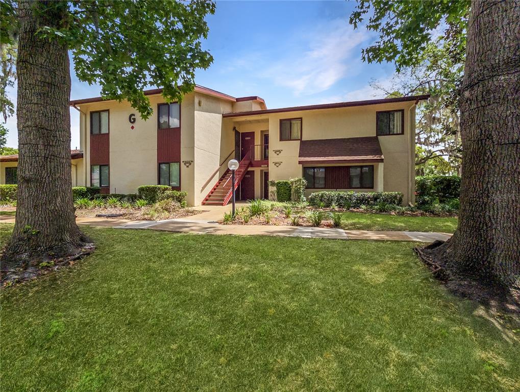 A two-story apartment building with tan stucco walls and a red staircase exterior — 646 MIDWAY DRIVE UNIT A, OCALA, FL