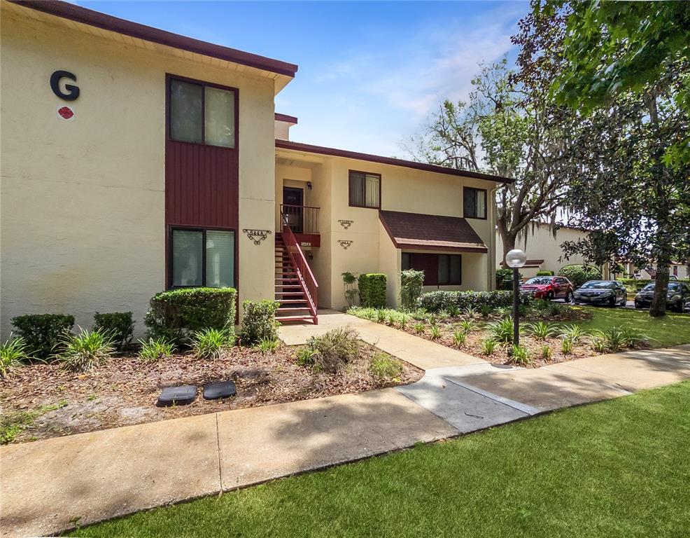 A two-story apartment building exterior features tan stucco walls, brown trim, and a central staircase — 646 MIDWAY DRIVE UNIT A, OCALA, FL