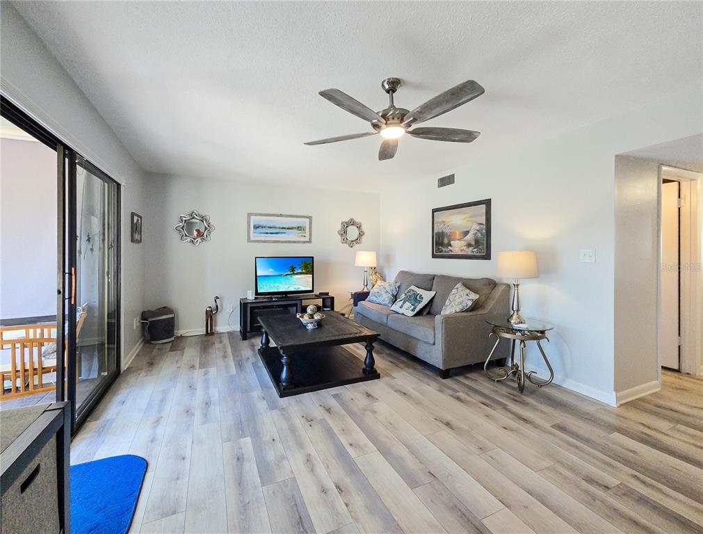 A living room features light wood-look flooring, a gray sofa, and a ceiling fan — 646 MIDWAY DRIVE UNIT A, OCALA, FL