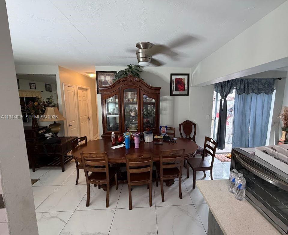 A dining room features a wooden table and hutch, tile flooring, and a ceiling fan — 7570 Miramar Pkwy, Miramar FL 33023, MIRAMAR, FL