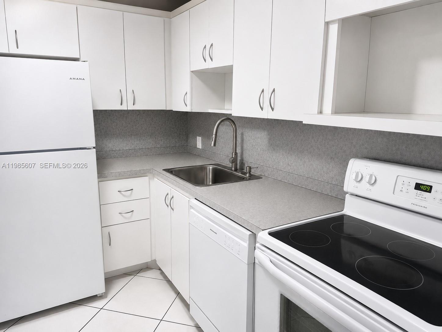 A kitchen features white cabinets, a stainless steel sink, and white appliances — 3675 N Country Club Dr # 508, Aventura FL 33180, AVENTURA, FL