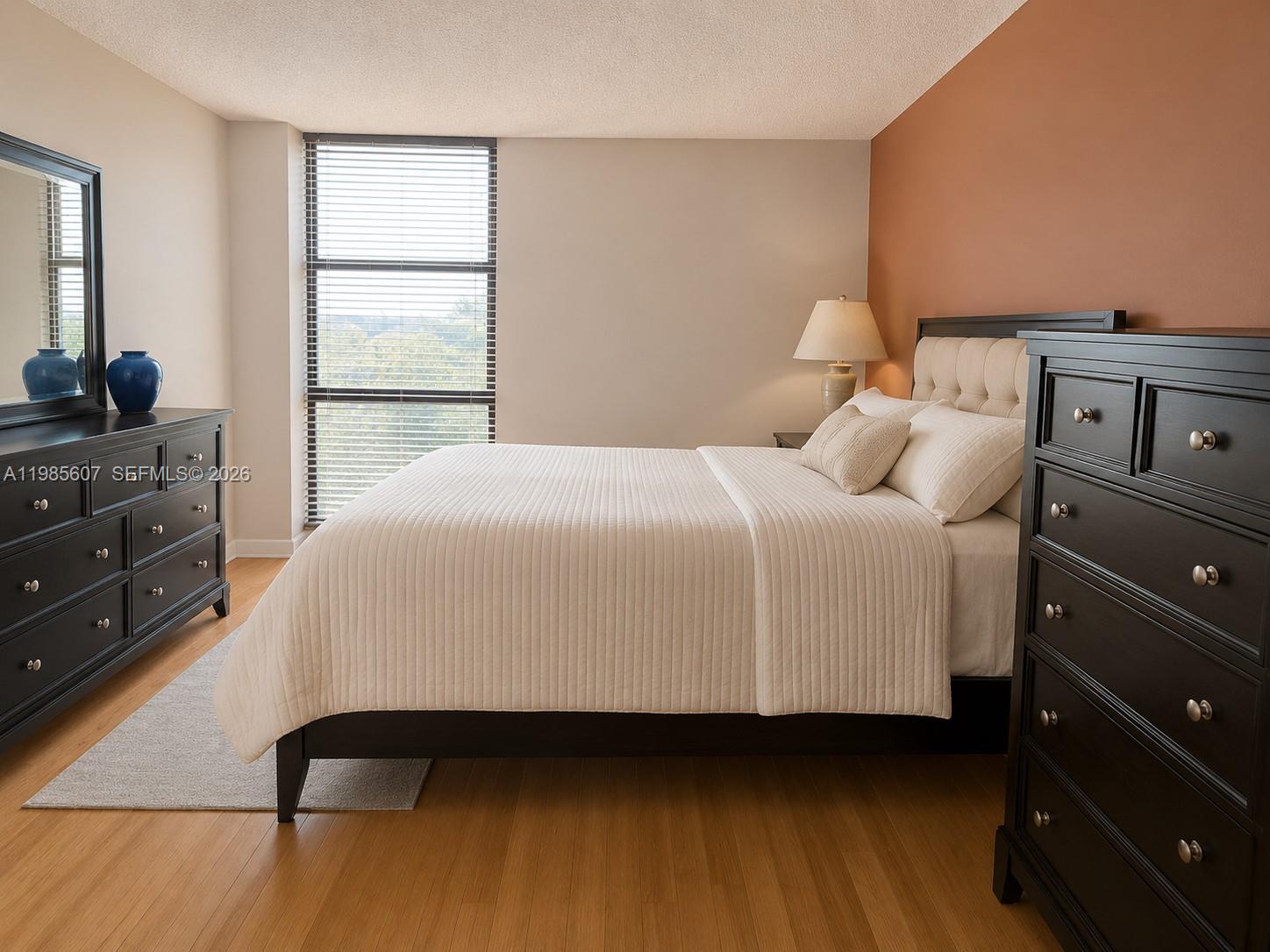 A bedroom features a bed, dark wood furniture, a window with blinds, and wood flooring — 3675 N Country Club Dr # 508, Aventura FL 33180, AVENTURA, FL