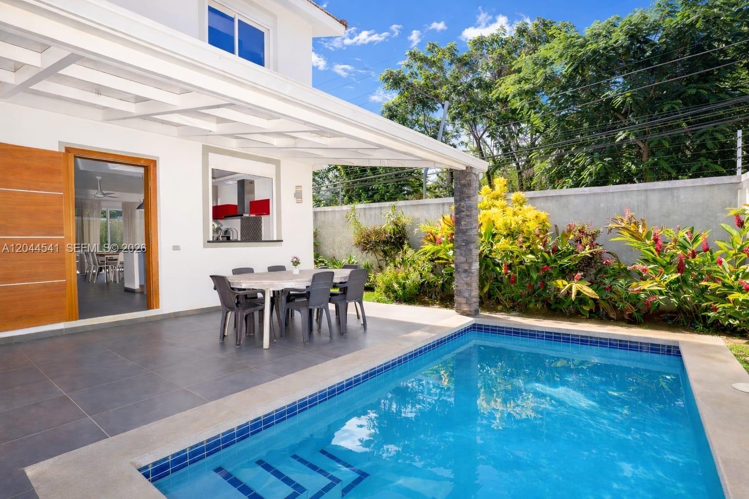 A patio with a dining set and swimming pool sits beside a house with landscaping — oo CALLE MARIANO VANDERHORST, FL 32000, FL