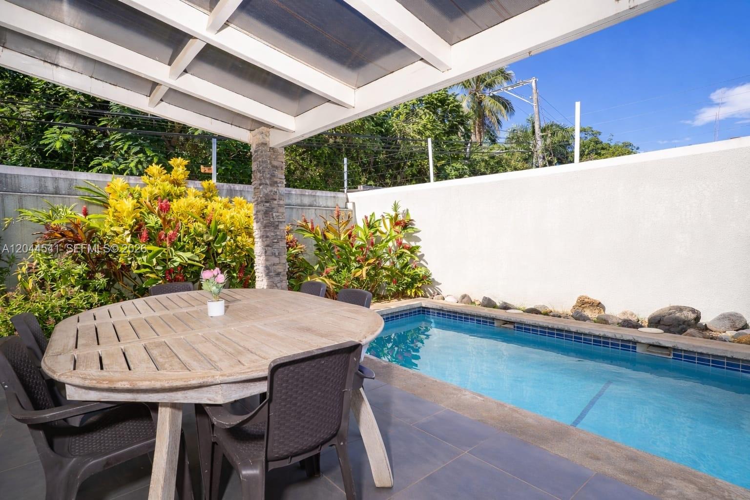 A patio with a round wooden table, chairs, and a small swimming pool — oo CALLE MARIANO VANDERHORST, FL 32000, FL