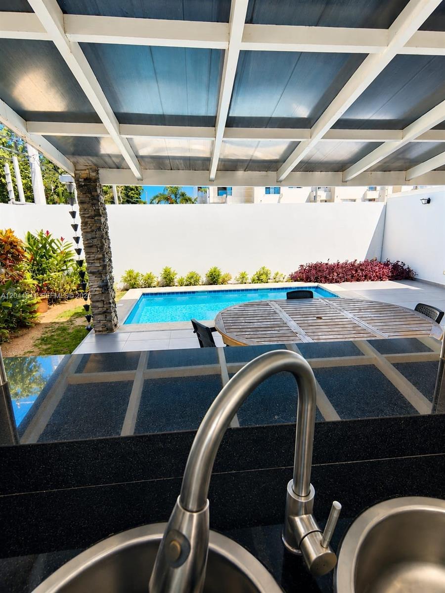 A view from an outdoor kitchen sink overlooking a patio, dining table, and swimming pool — oo CALLE MARIANO VANDERHORST, FL 32000, FL