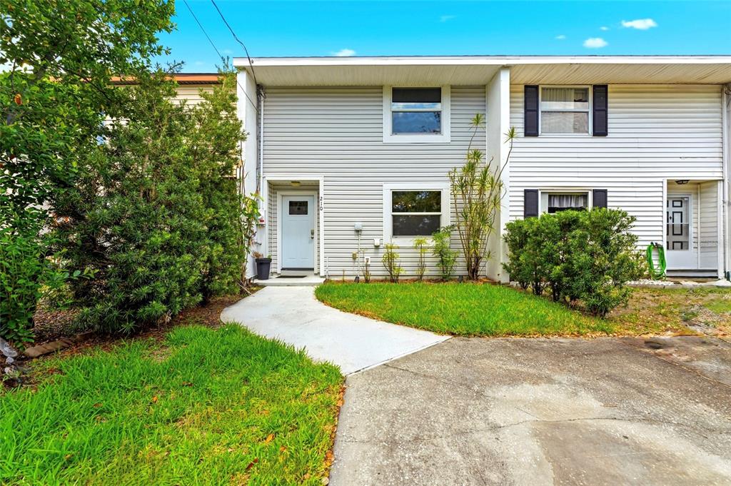 A two-story townhouse exterior features light gray siding, a concrete walkway, and a small lawn — 210 S MALCOLM COURT, TAMPA, FL