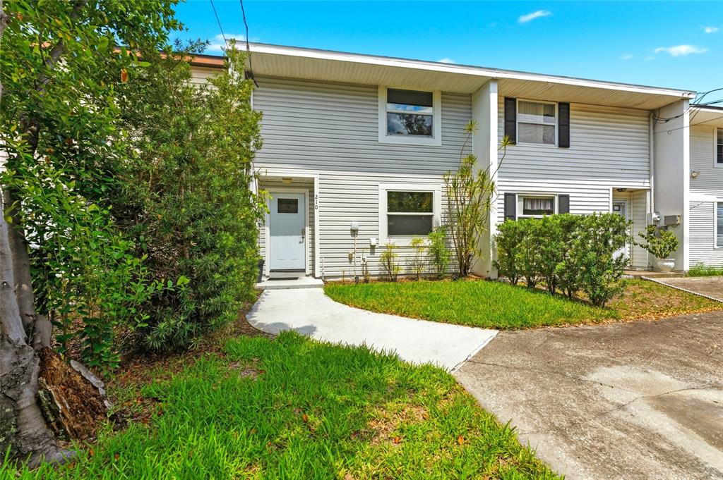 A two-story townhouse with light gray siding, a white front door, and a concrete walkway — 210 S MALCOLM COURT, TAMPA, FL