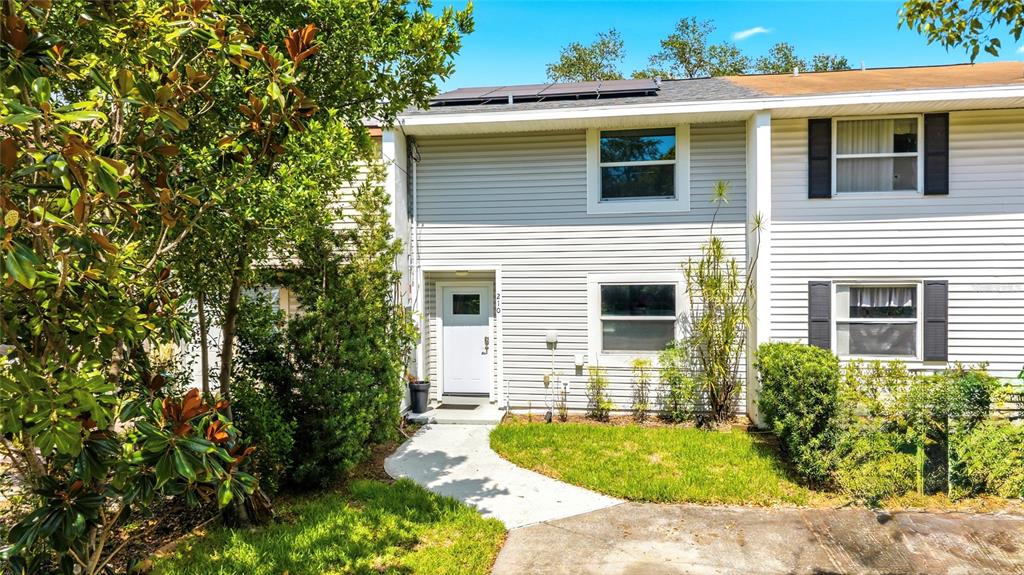 A two-story townhouse exterior features light gray siding, a white front door, and solar panels — 210 S MALCOLM COURT, TAMPA, FL