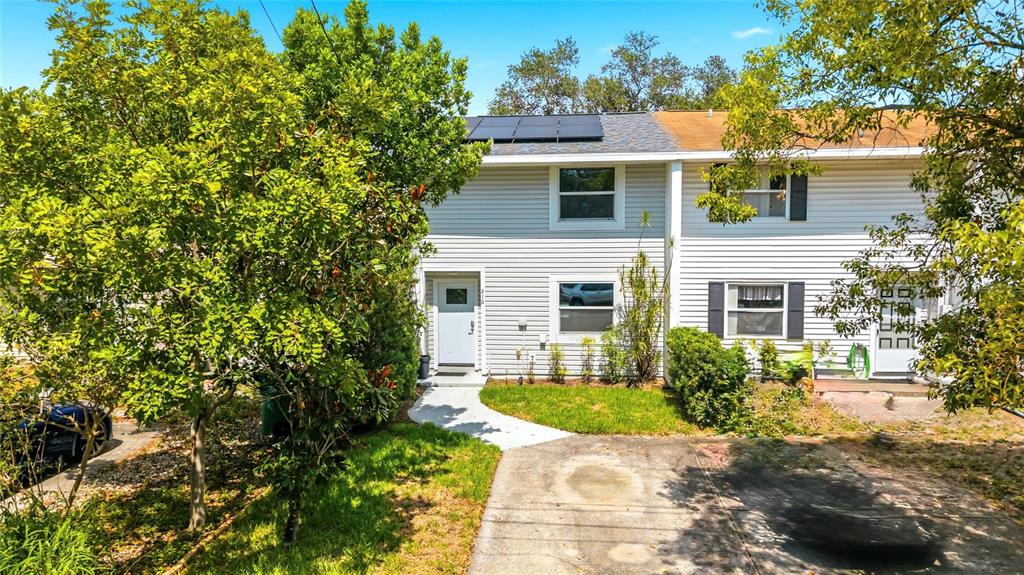 A two-story townhouse with white siding, a concrete driveway, and solar panels on the roof — 210 S MALCOLM COURT, TAMPA, FL