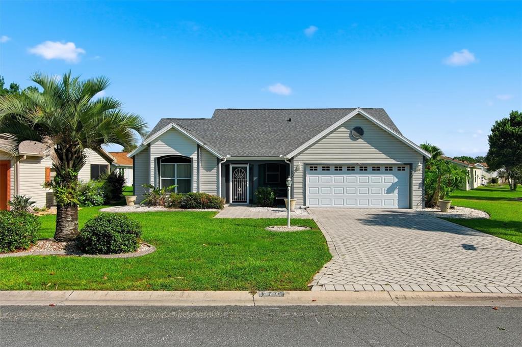 A single-story house with light gray siding, a two-car garage, and a paved driveway — 1260 GRANADA COURT, LADY LAKE, FL