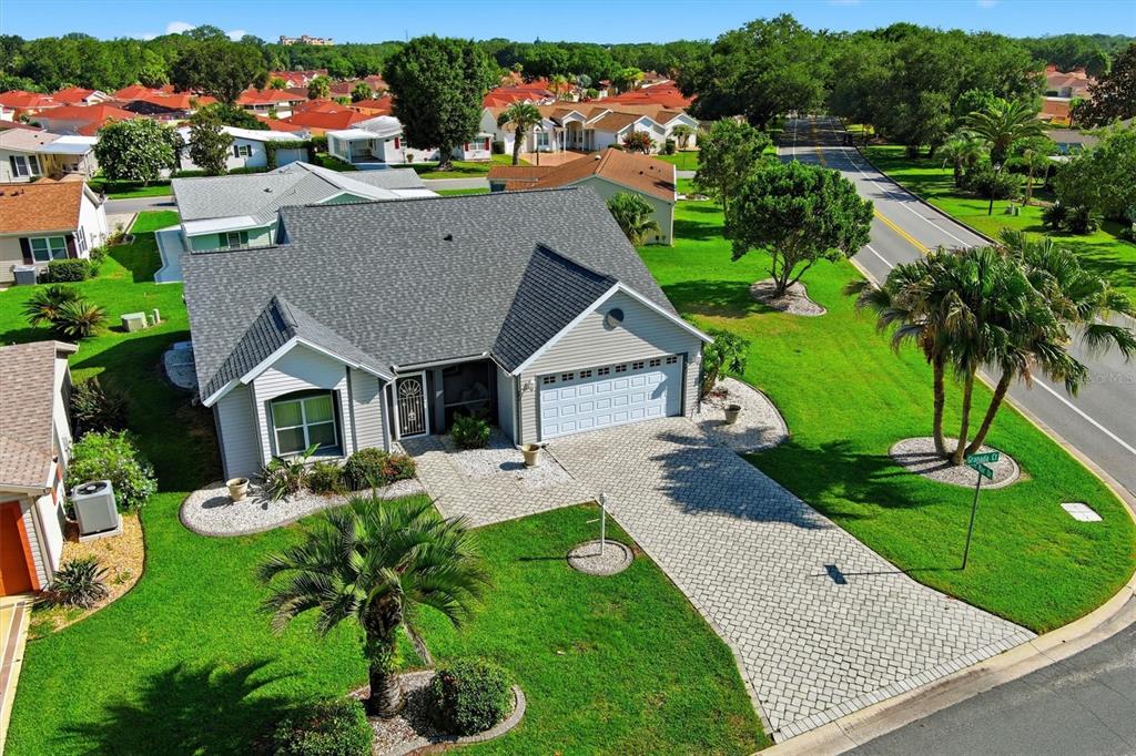 An aerial view shows a single-story house with a gray roof, garage, and paved driveway — 1260 GRANADA COURT, LADY LAKE, FL