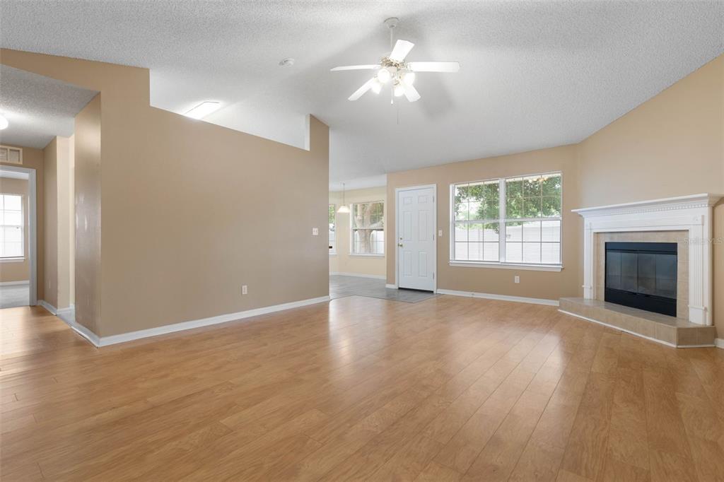 A living room with light wood flooring, a fireplace, and a ceiling fan — 84 BRUNSWICK LANE, PALM COAST, FL