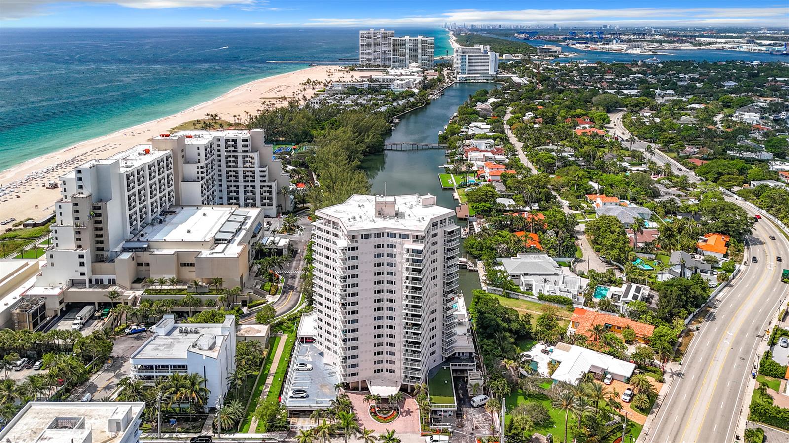 An aerial view shows a high-rise building near a beach, a canal, and a road — 3000 Holiday Drive # 1505, Fort Lauderdale FL 33316, FORT LAUDERDALE, FL