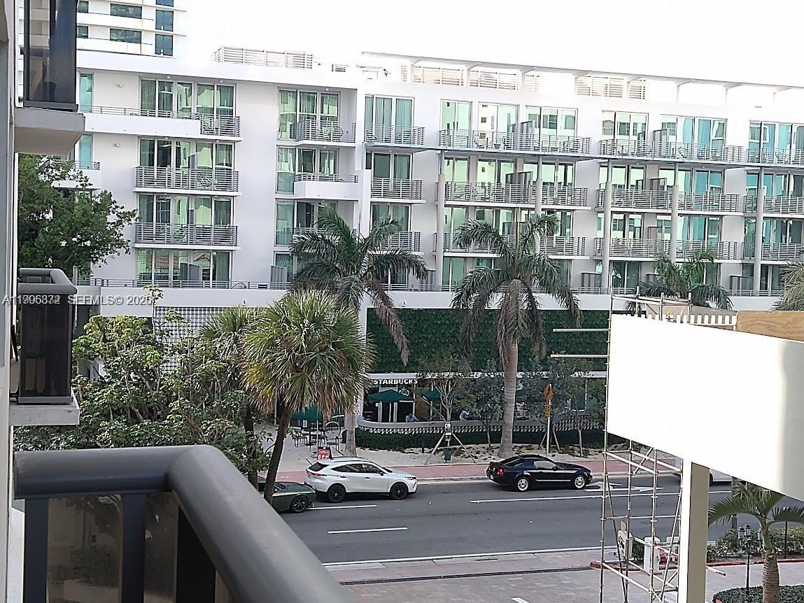 An exterior view shows a multi-story white apartment building with balconies and a ground-level Starbucks — 6039 Collins Ave # 407, Miami Beach FL 33140, MIAMI BEACH, FL