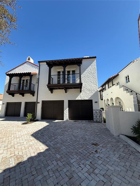 A white stucco house with two dark garage doors and two wooden balconies under a clear sky — 301 W COMSTOCK AVENUE, WINTER PARK, FL