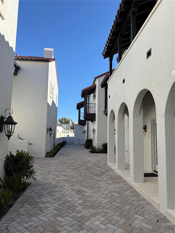 A paved walkway leads between two white stucco buildings with arched porticos and tile roofs — 301 W COMSTOCK AVENUE, WINTER PARK, FL