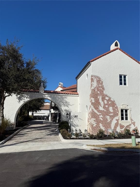 A white stucco building with a brick accent wall and a large arched driveway entrance — 301 W COMSTOCK AVENUE, WINTER PARK, FL