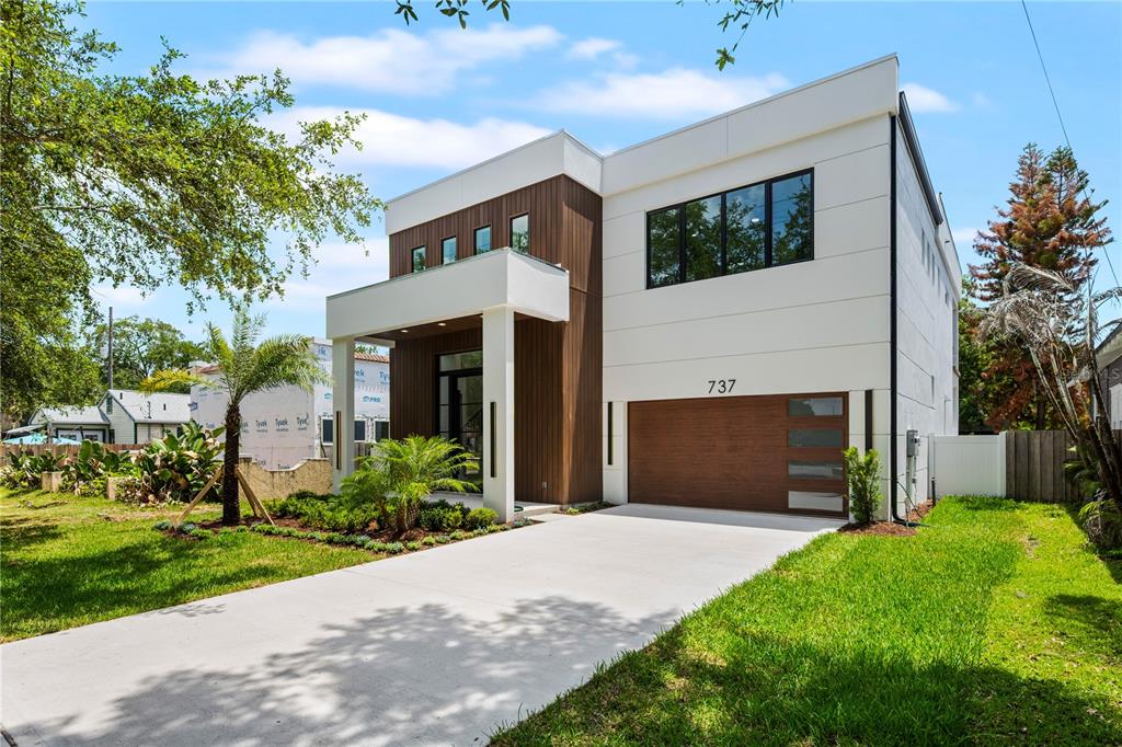 A modern two-story house features a white exterior, wood-paneled accents, and a two-car garage — 737 N SUMMERLIN AVENUE, ORLANDO, FL