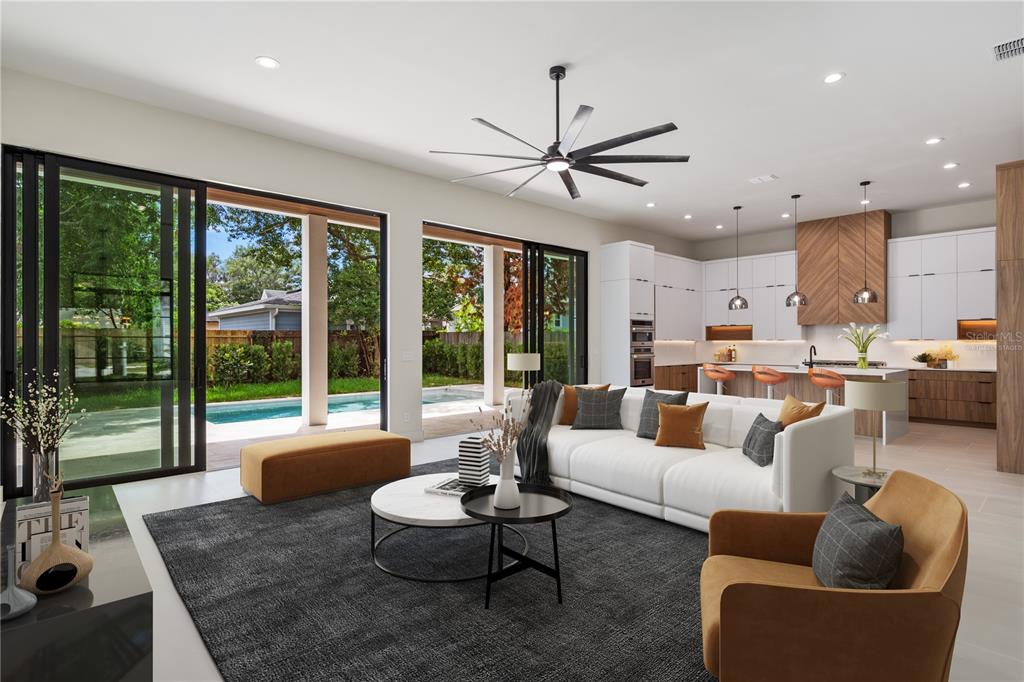 A modern open-concept living room and kitchen feature sliding glass doors overlooking a backyard pool — 737 N SUMMERLIN AVENUE, ORLANDO, FL