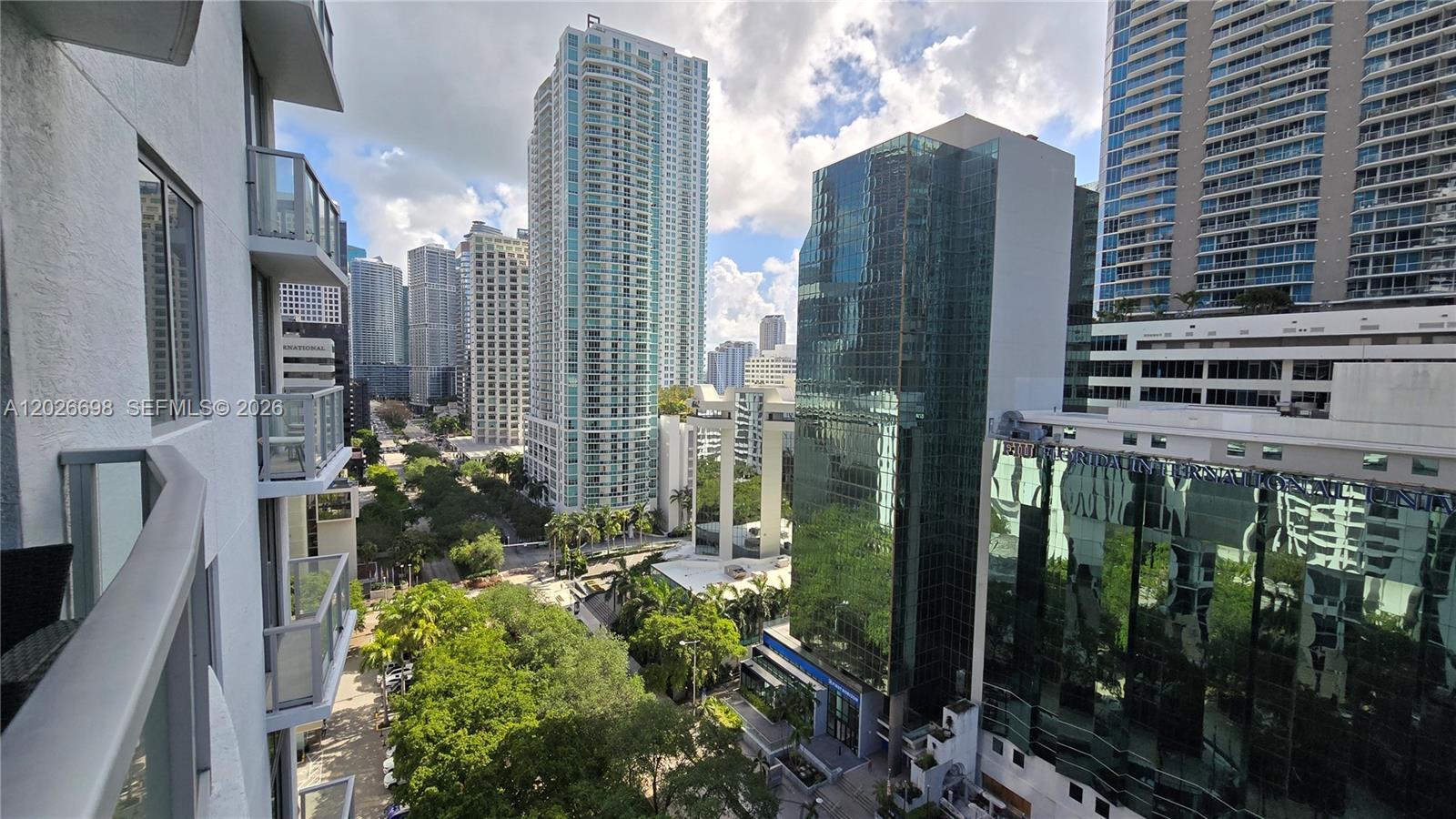 A high-angle view shows a city street lined with tall glass skyscrapers and lush trees — 1060 Brickell Ave # 1503, Miami FL 33131, MIAMI, FL
