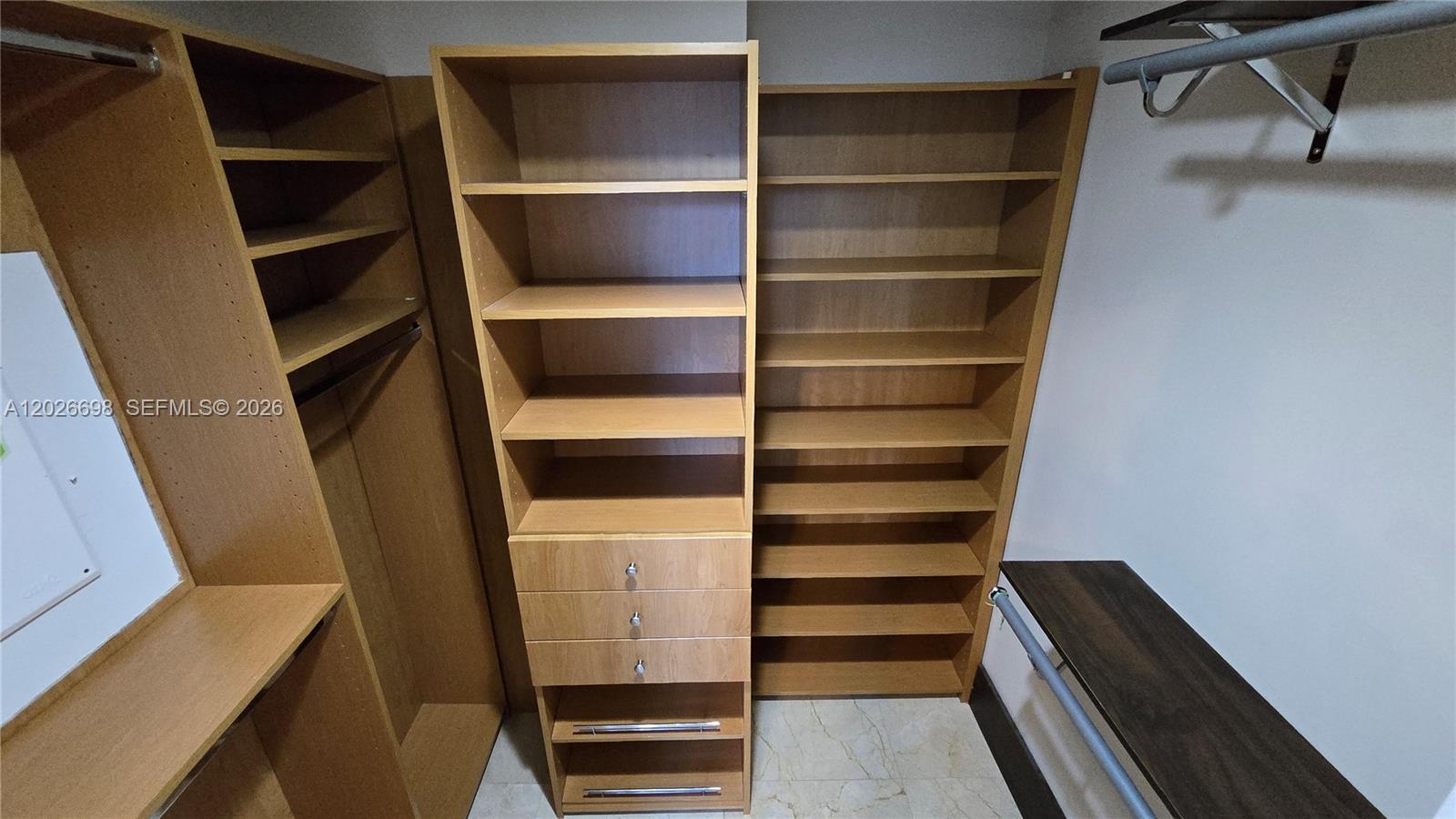 A walk-in closet features light wood shelving, built-in drawers, and metal clothing rods — 1060 Brickell Ave # 1503, Miami FL 33131, MIAMI, FL