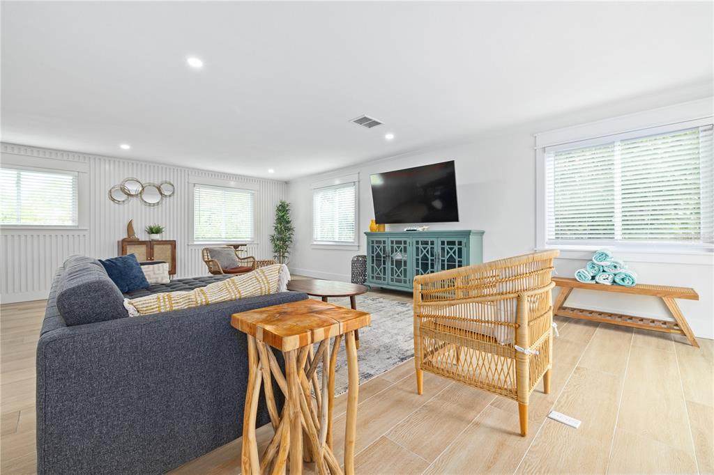 A living room features a grey sofa, a rattan chair, and a teal media console — 228 GLADIOLUS STREET, ANNA MARIA, FL