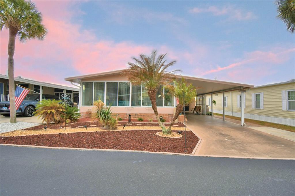 A single-story manufactured home with a carport, palm trees, and a landscaped front yard — 4056 ROLLING OAKS DRIVE, WINTER HAVEN, FL