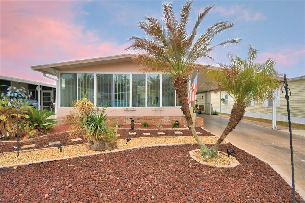 A manufactured home features a large sunroom, a carport, and a landscaped front yard — 4056 ROLLING OAKS DRIVE, WINTER HAVEN, FL