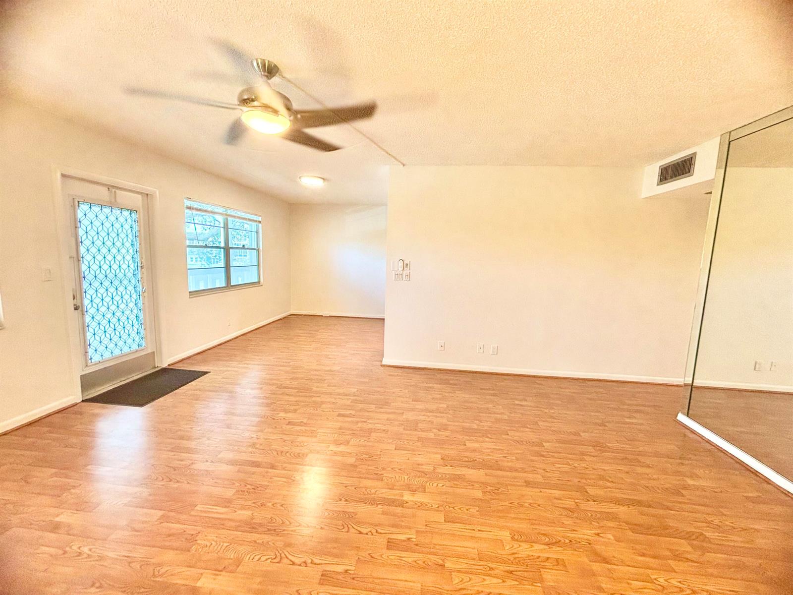 An empty living room with light wood-look flooring, a ceiling fan, and a glass door — 2069 Oakridge F Unit 2069, Deerfield Beach FL 33442, DEERFIELD BEACH, FL