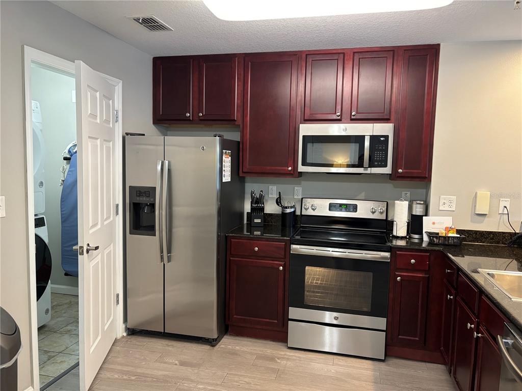 A kitchen with dark wood cabinets, stainless steel appliances, and light wood-look flooring — 14501 GROVE RESORT AVENUE UNIT 1224, WINTER GARDEN, FL