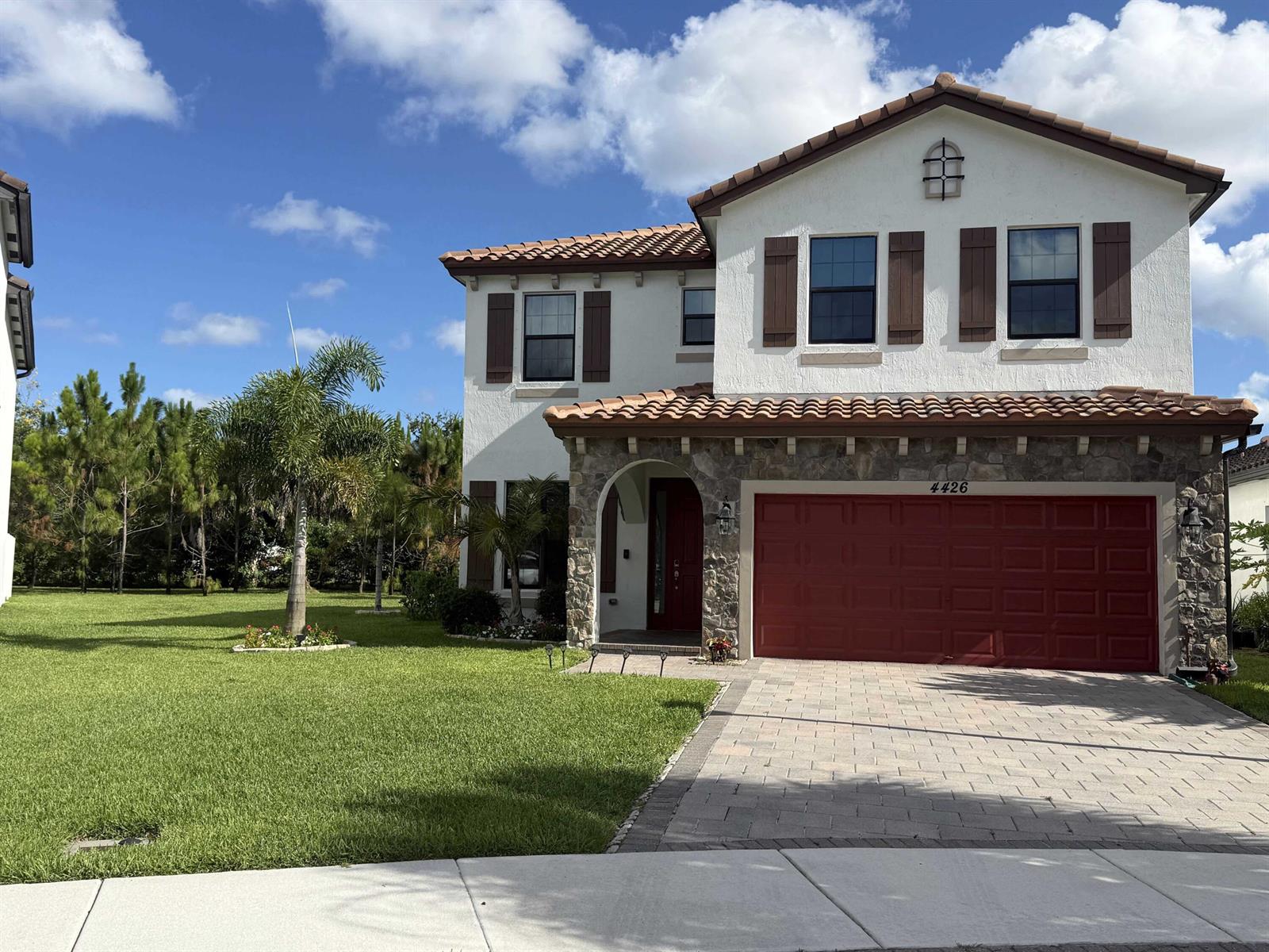 A two-story house with a red garage door, stone facade, and a tiled roof — 4426 Buena Tara Drive, FL 33413, FL