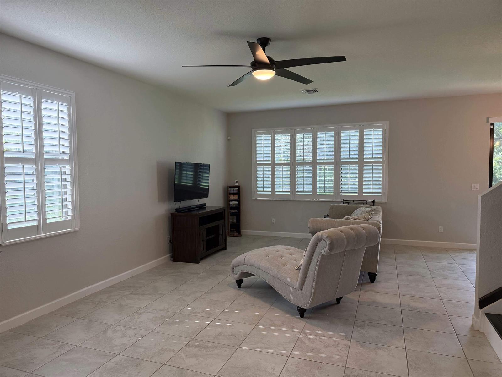 A living room features light tile flooring, plantation shutters, a ceiling fan, and two chaise lounges — 4426 Buena Tara Drive, FL 33413, FL