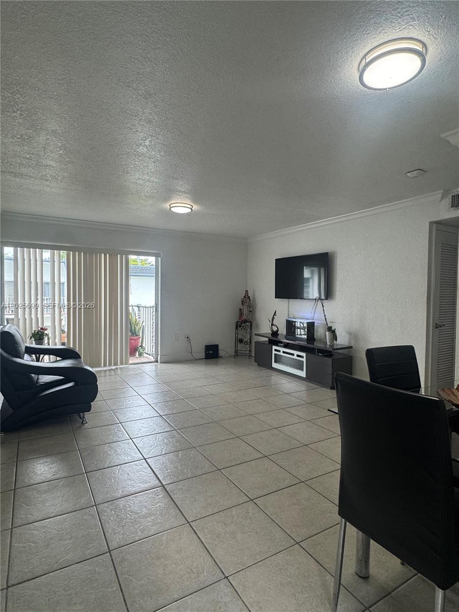 A living room features light tile flooring, a mounted television, and sliding glass balcony doors — 7235 SW 94th Pl # J6, Miami FL 33173, MIAMI, FL