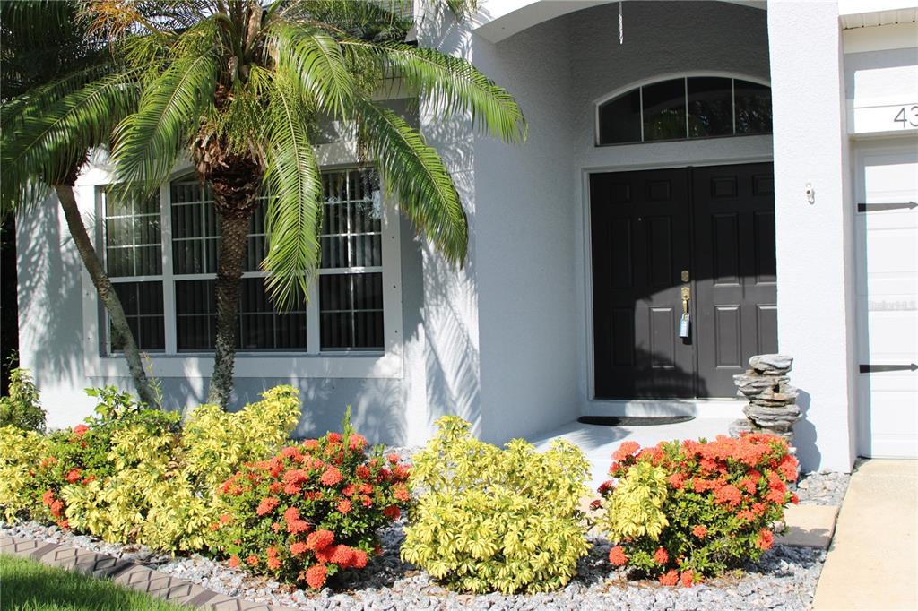 A white house exterior features a dark double front door and a landscaped garden bed — 433 YORK DALE DRIVE, RUSKIN, FL