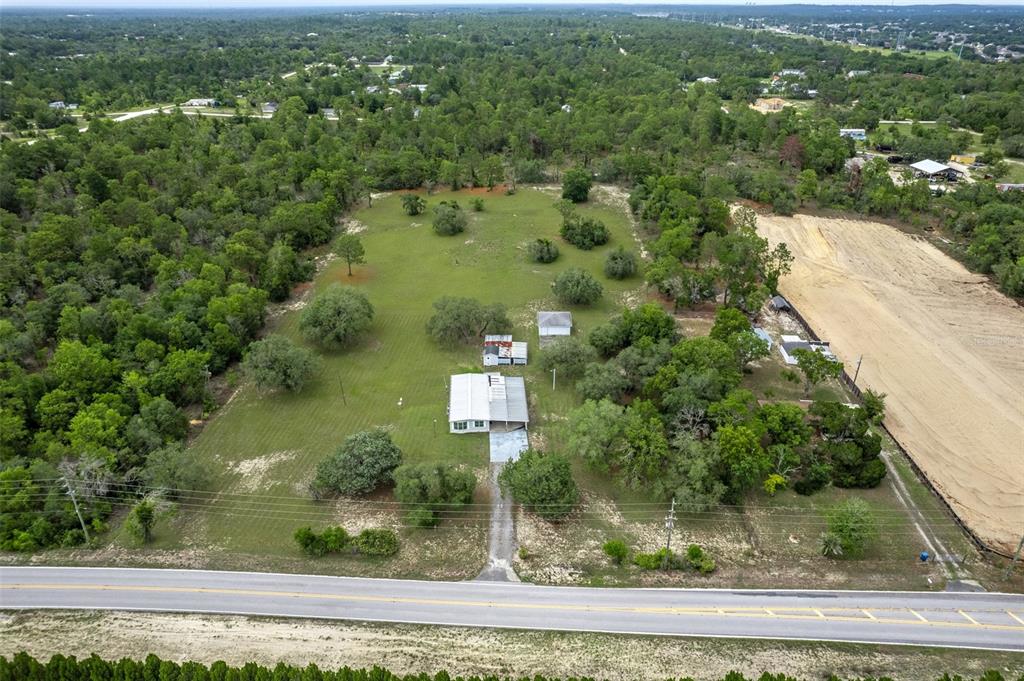An aerial view shows a house with a metal roof on a large, grassy lot — 13255 JACQUELINE ROAD, BROOKSVILLE, FL