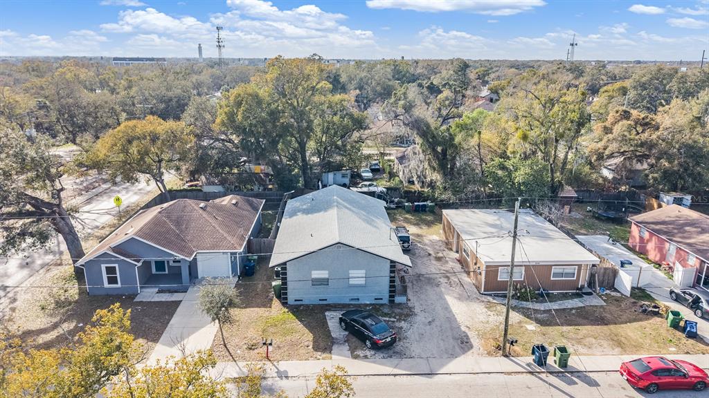 An aerial view shows three residential houses with driveways and trees in a suburban neighborhood — 8304 N 13TH STREET, TAMPA, FL