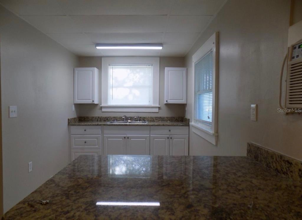 A kitchen features white cabinets, granite countertops, and a window above the sink — 626 HIGHLAND STREET N, ST PETERSBURG, FL