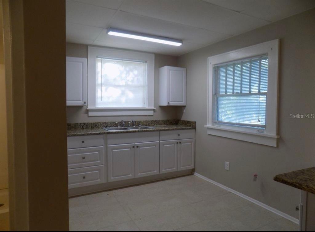 A kitchen features white cabinets, granite countertops, a double sink, and two windows — 626 HIGHLAND STREET N, ST PETERSBURG, FL