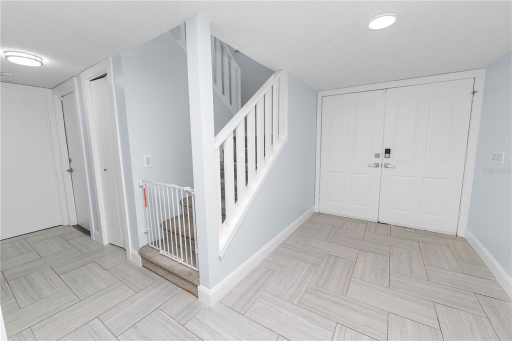 An entryway features light-colored tile flooring, a staircase with a white railing, and double doors — 1224 RAINBROOK CIRCLE, VALRICO, FL