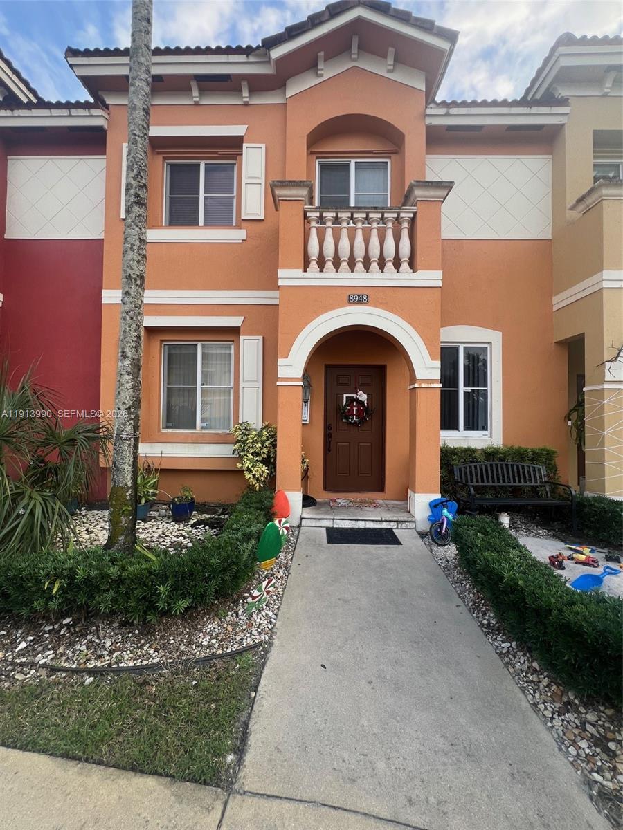 A two-story orange stucco townhouse features a front entrance with a balcony and arched doorway — 8948 SW 19th St # 909, Miramar FL 33025, MIRAMAR, FL