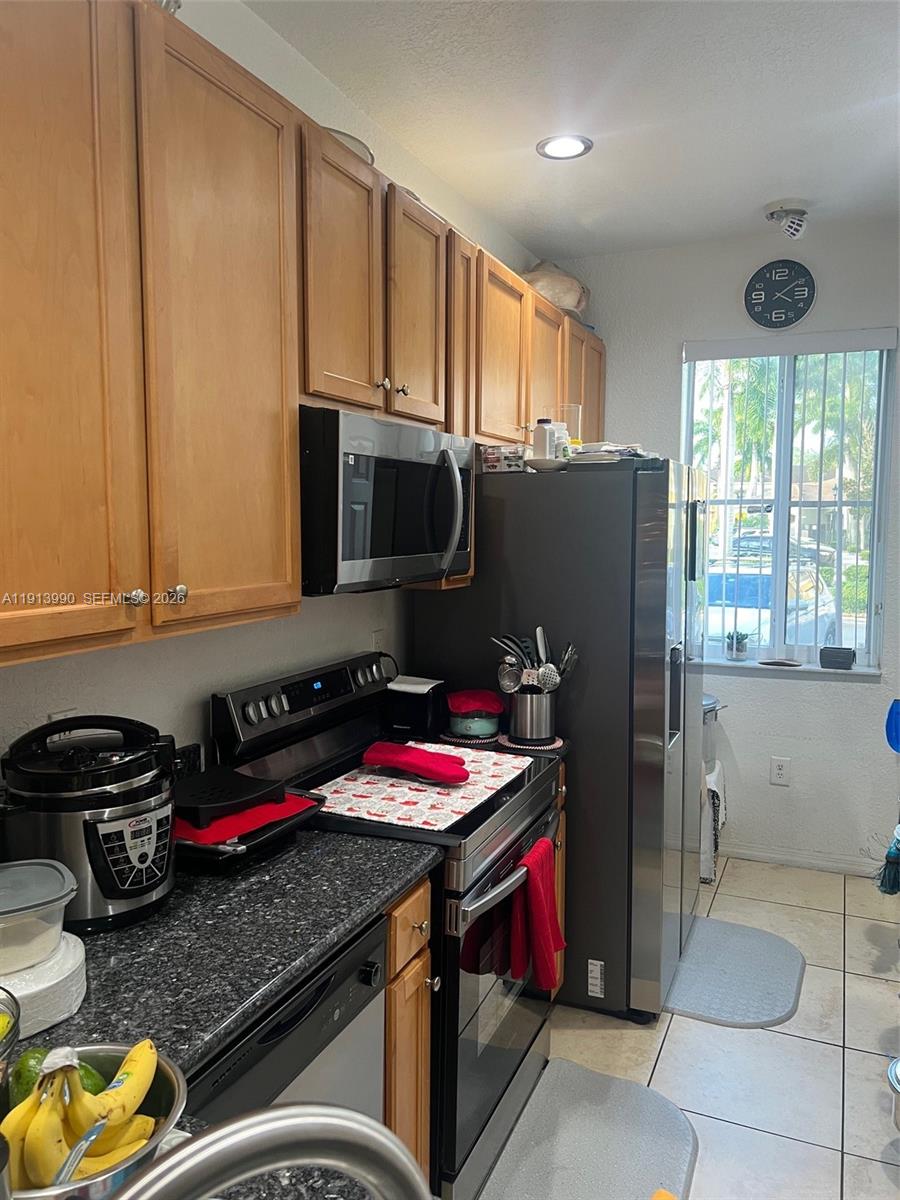 A kitchen with wood cabinets, stainless steel appliances, and a dark granite countertop — 8948 SW 19th St # 909, Miramar FL 33025, MIRAMAR, FL