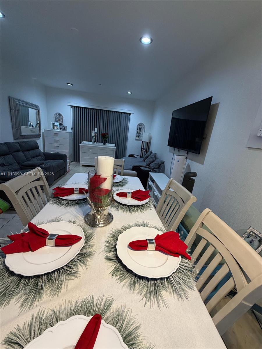 A dining room features a table set for dinner with red napkins and white chairs — 8948 SW 19th St # 909, Miramar FL 33025, MIRAMAR, FL